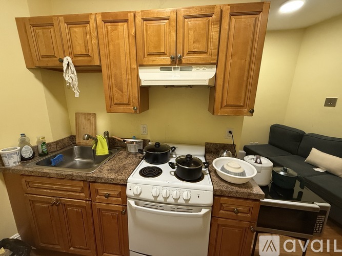 A kitchen with a stove top oven and wooden cabinets.