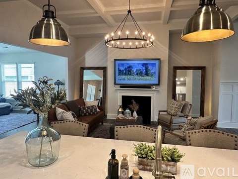 A living room with a fireplace and a television mounted above it.