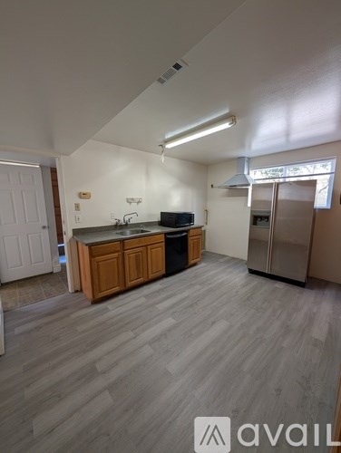 A kitchen with wooden cabinets and a grey floor.
