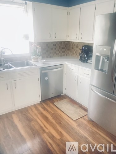 A kitchen with white cabinets and a wooden floor.