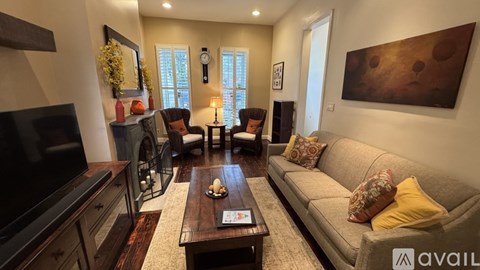 A living room with a grey couch, a wooden coffee table, and a large painting on the wall.