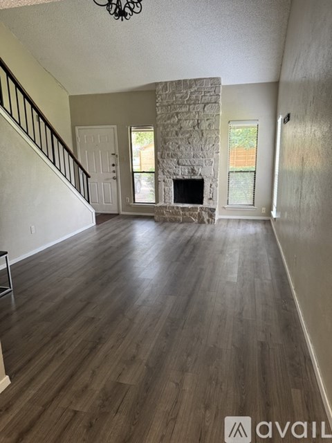 A living room with a stone fireplace and wood flooring.
