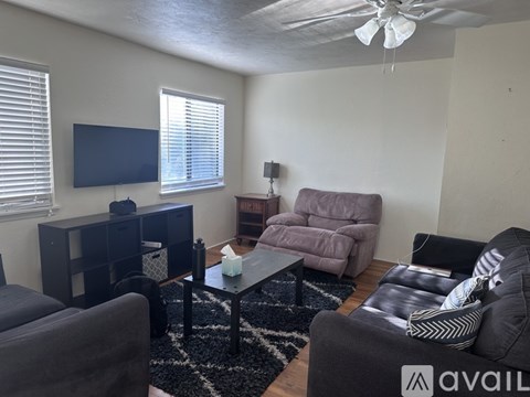 A living room with a grey couch, a black coffee table, and a television on the wall.