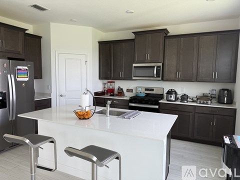 A kitchen with a white island and dark brown cabinets.
