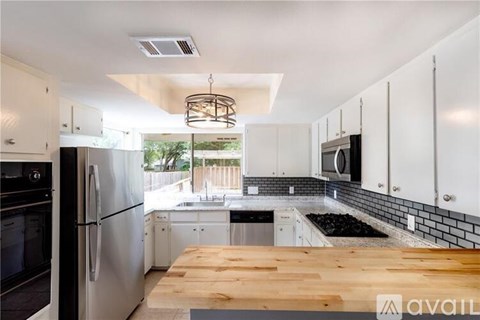 A kitchen with white cabinets and a wooden table.