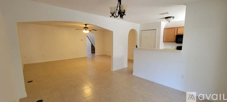 A spacious room with a fan and a chandelier.