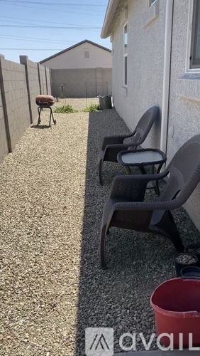 A patio with chairs and a red bucket on the ground.