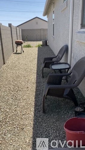 A patio with chairs and a red bucket on the ground.