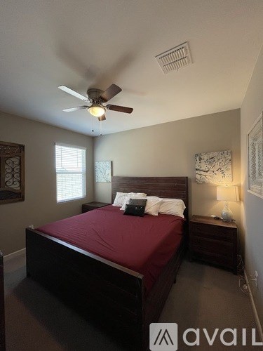 A bedroom with a bed, nightstand, and ceiling fan.