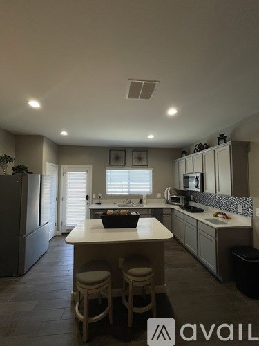 A kitchen with a table and chairs in front of a refrigerator.