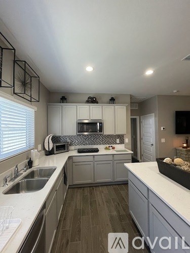 A kitchen with a sink, stove, and cabinets.