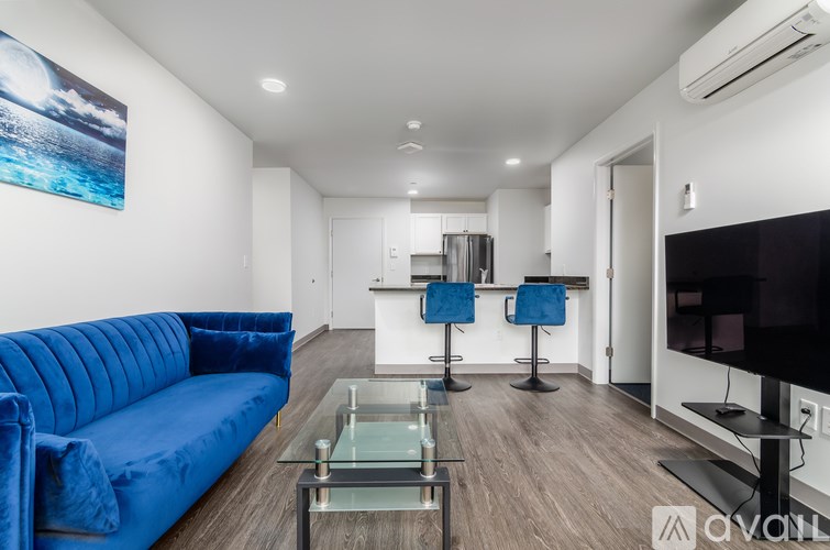 A living room with a blue couch and a glass coffee table.