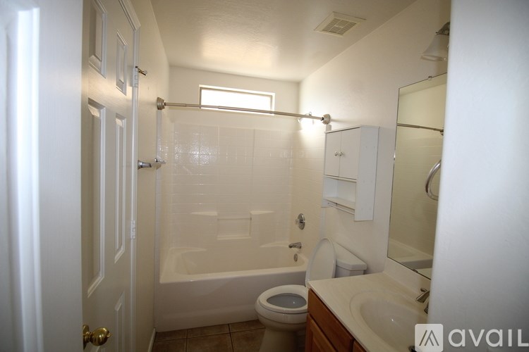 A spacious empty room with a door, a window, and a ceiling fan.