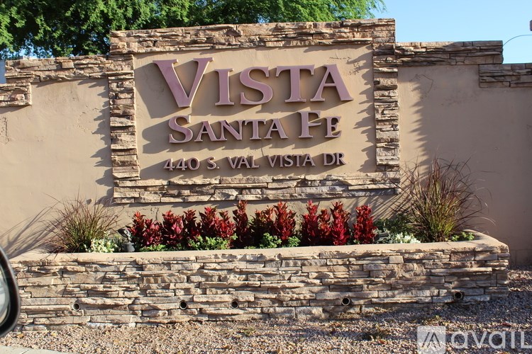 A sign for Vista Santa Fe with a stone wall and plants in front.