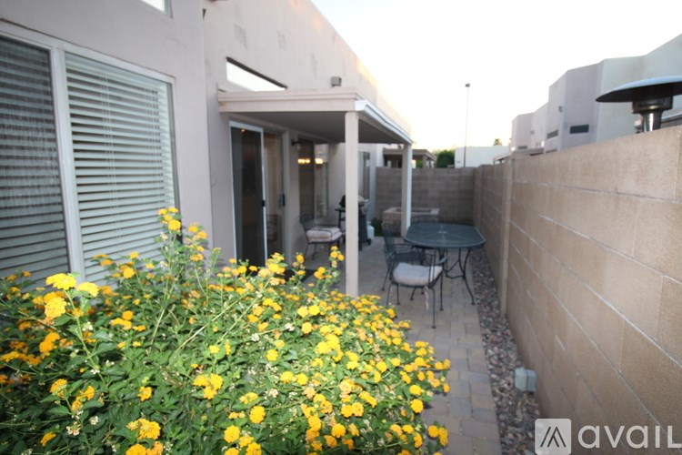 A patio with a table and chairs is surrounded by yellow flowers.