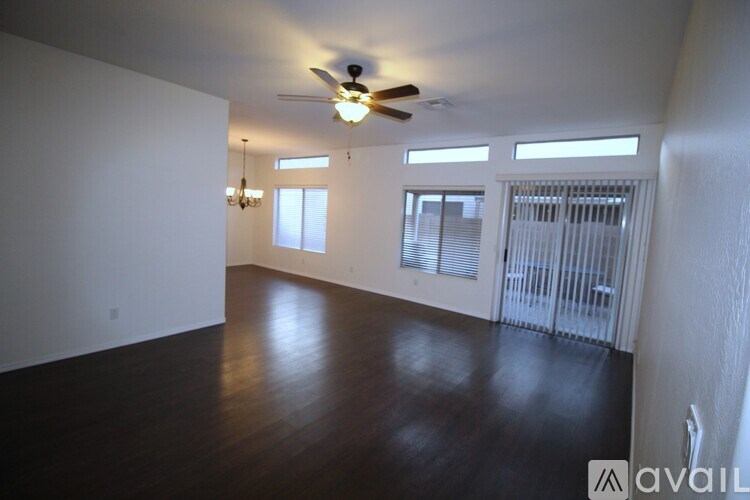 A spacious room with a ceiling fan and wooden flooring.