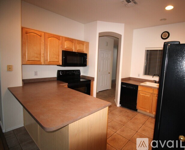 A kitchen with a black fridge and wooden cabinets.