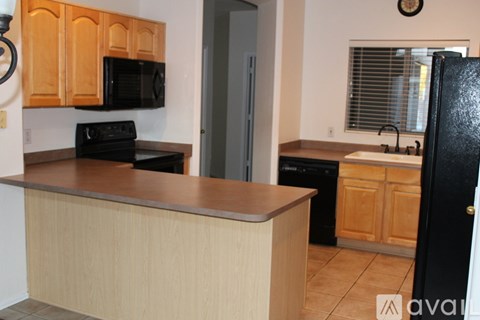 A kitchen with wooden cabinets and a black refrigerator.