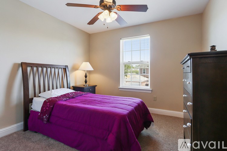 A bedroom with a purple bedspread and a ceiling fan.