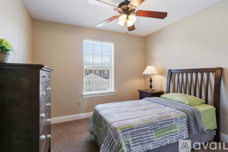 A bedroom with a bed, dresser, and window.