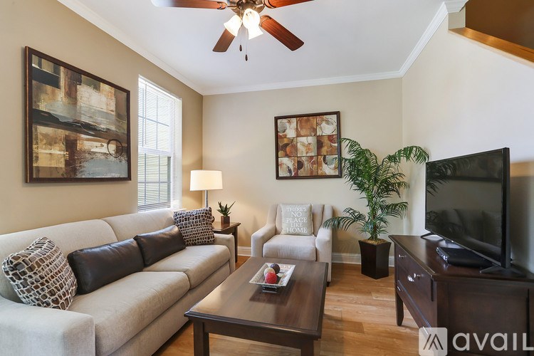 A living room with a couch, a chair, a coffee table, a television, and a plant.