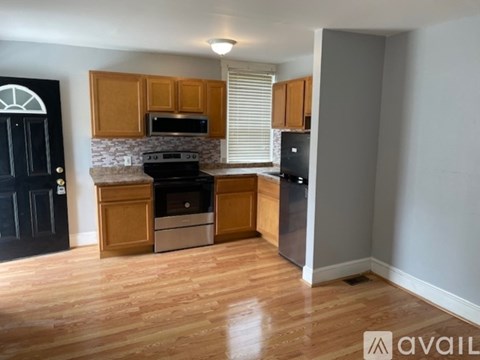 A kitchen with wooden cabinets and a black door.