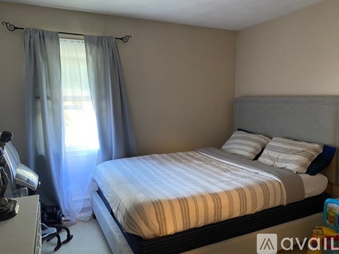 A bedroom with a bed, pillows, and a window with curtains.