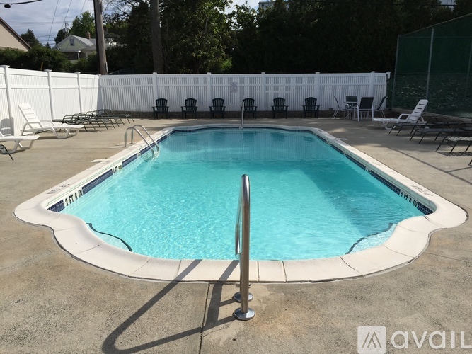 A pool surrounded by white fencing and chairs.