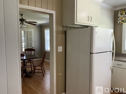 A kitchen with a white refrigerator and a dining table with chairs.