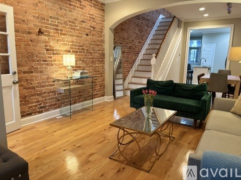 A living room with a green couch and a glass coffee table.