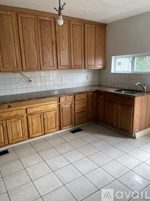 A kitchen with wooden cabinets and a tiled floor.