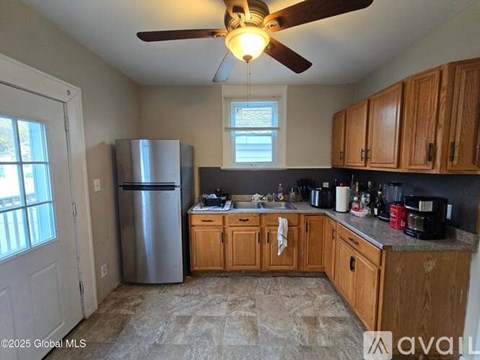 A kitchen with wooden cabinets and a ceiling fan.