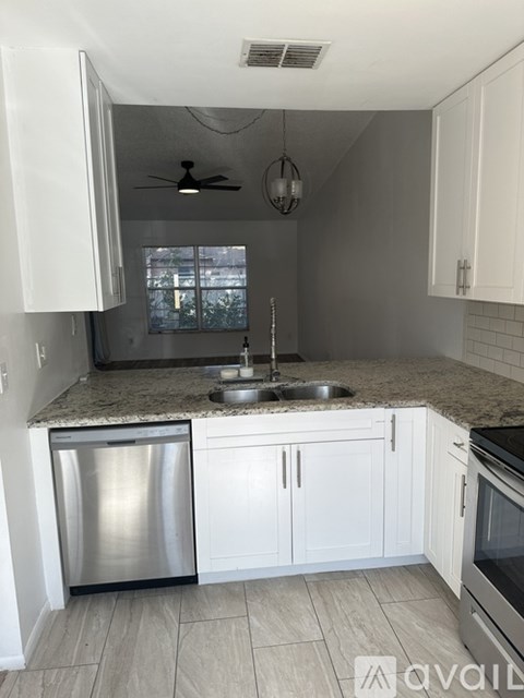 A kitchen with white cabinets and a stainless steel dishwasher.