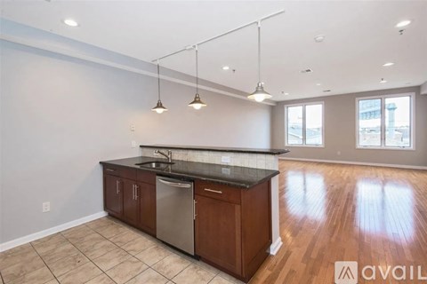 A kitchen with wooden cabinets and a black countertop is available for rent.