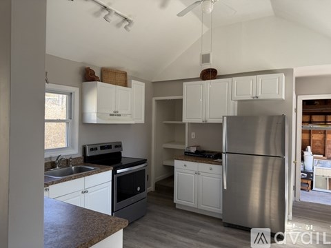 A kitchen with white cabinets and a stainless steel refrigerator.