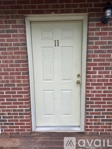 A white door with a gold handle is set in a brick wall.