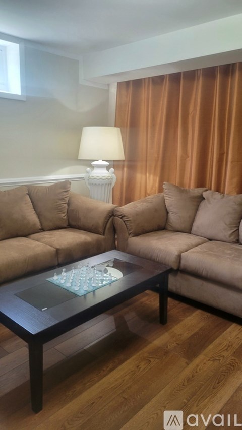 A living room with a brown sofa and a glass coffee table.