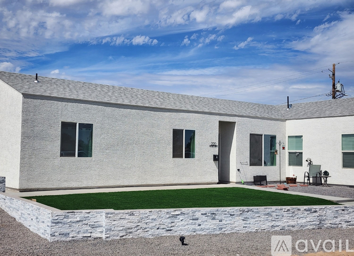A modern house with a grey exterior and a green lawn in front.