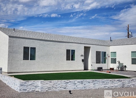 A modern house with a grey exterior and a green lawn in front.