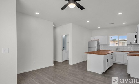 A spacious kitchen with white cabinets and a wooden countertop.