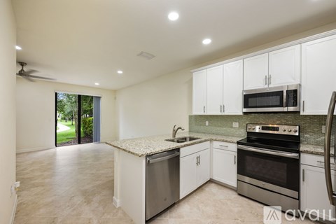A kitchen with white cabinets and stainless steel appliances is available for rent.