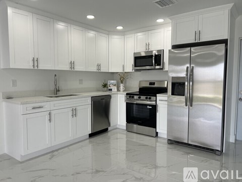 A modern kitchen with white cabinets and stainless steel appliances.