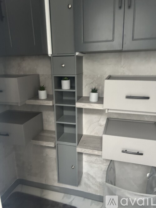 A kitchen with grey cabinets and a marble backsplash.