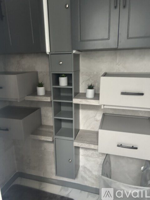 A kitchen with grey cabinets and a marble backsplash.