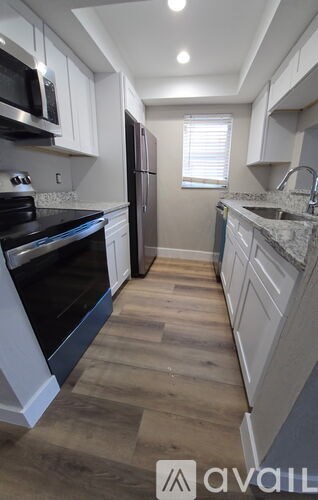 A kitchen with wooden floors and white cabinets.