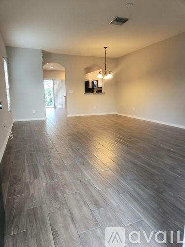 A spacious room with wooden flooring and a light fixture.
