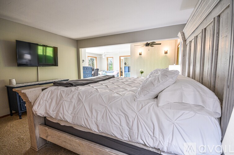 A bedroom with a large bed and a flat screen TV mounted on the wall.