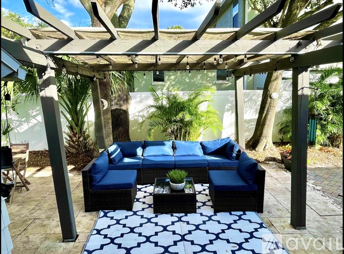 A patio with a blue couch and a white and black patterned rug.