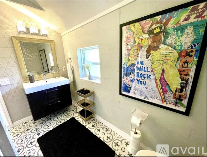 A bathroom with a large mirror, a sink, and a framed poster on the wall.