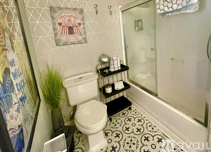 A bathroom with a toilet, a shelf with toiletries, and a shower.